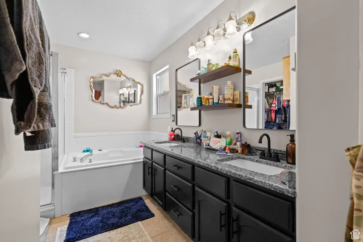 Bathroom featuring double vanity, a bath, and light tile patterned floors