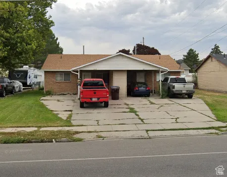 View of front of property with brick siding, driveway, and a front yard