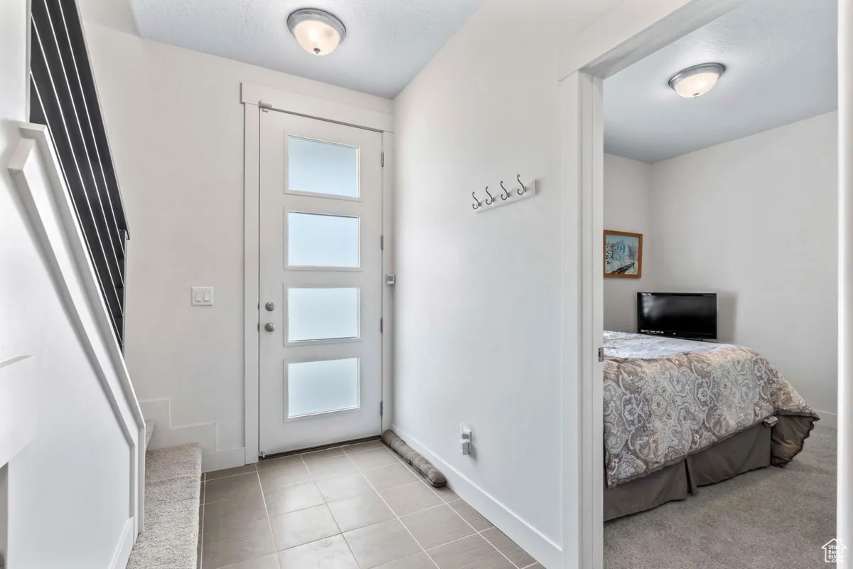 Entryway featuring light tile patterned floors, a textured ceiling, and stairway