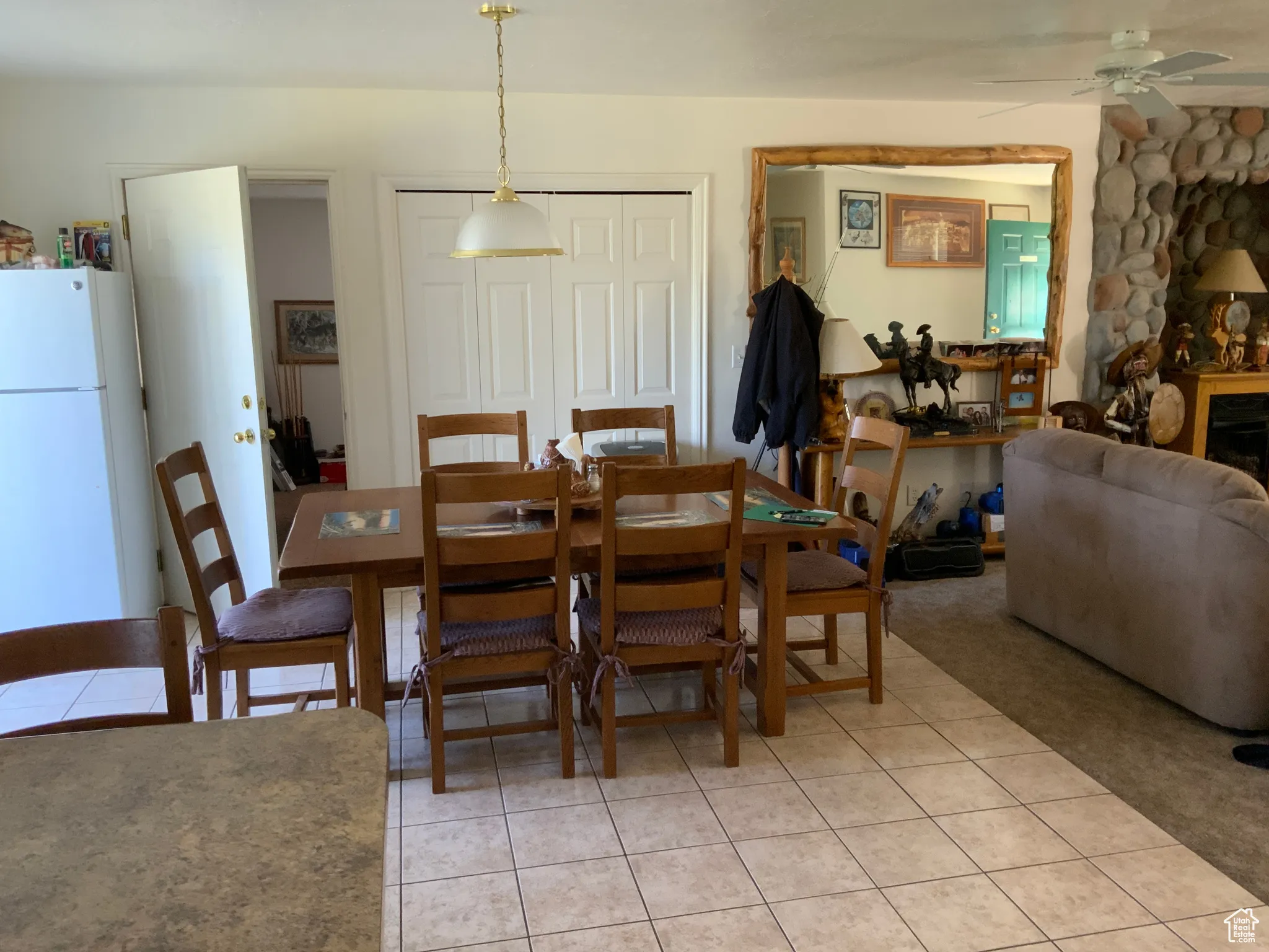 Dining area with light tile patterned floors, ceiling fan, a fireplace, and light colored carpet