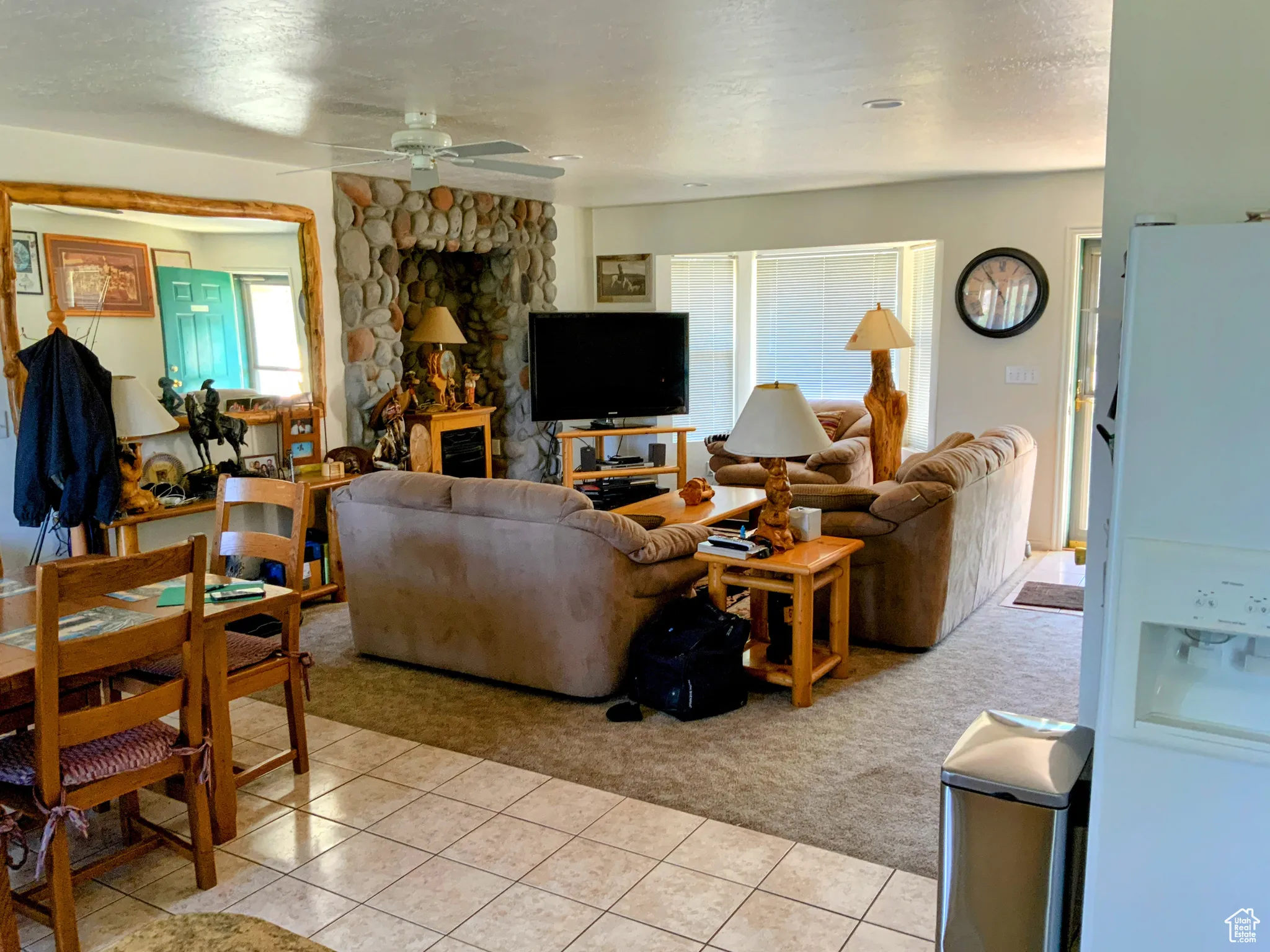 Living room with light colored carpet, a textured ceiling, a ceiling fan, and light tile patterned flooring
