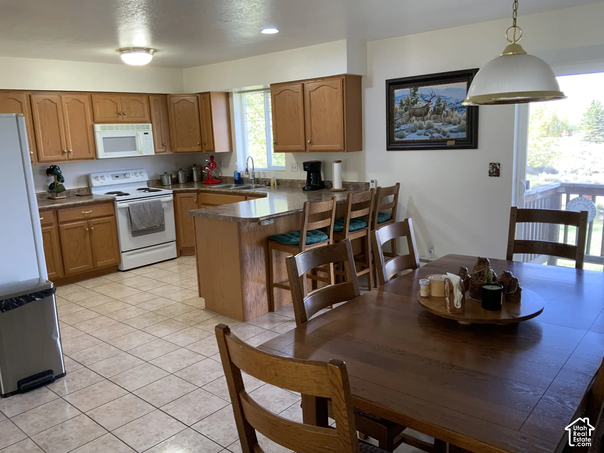 Kitchen featuring wood-finish cabinetry, white appliances, and a breakfast bar