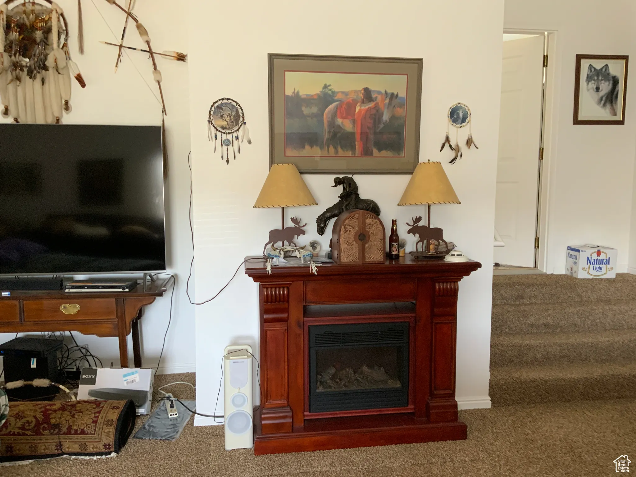 Living area featuring carpet, a glass covered fireplace, and stairway
