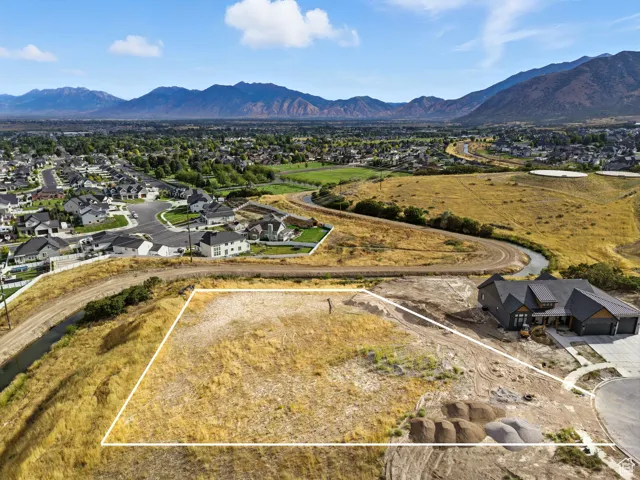 Aerial perspective of suburban area with property parcel outlined and mountains
