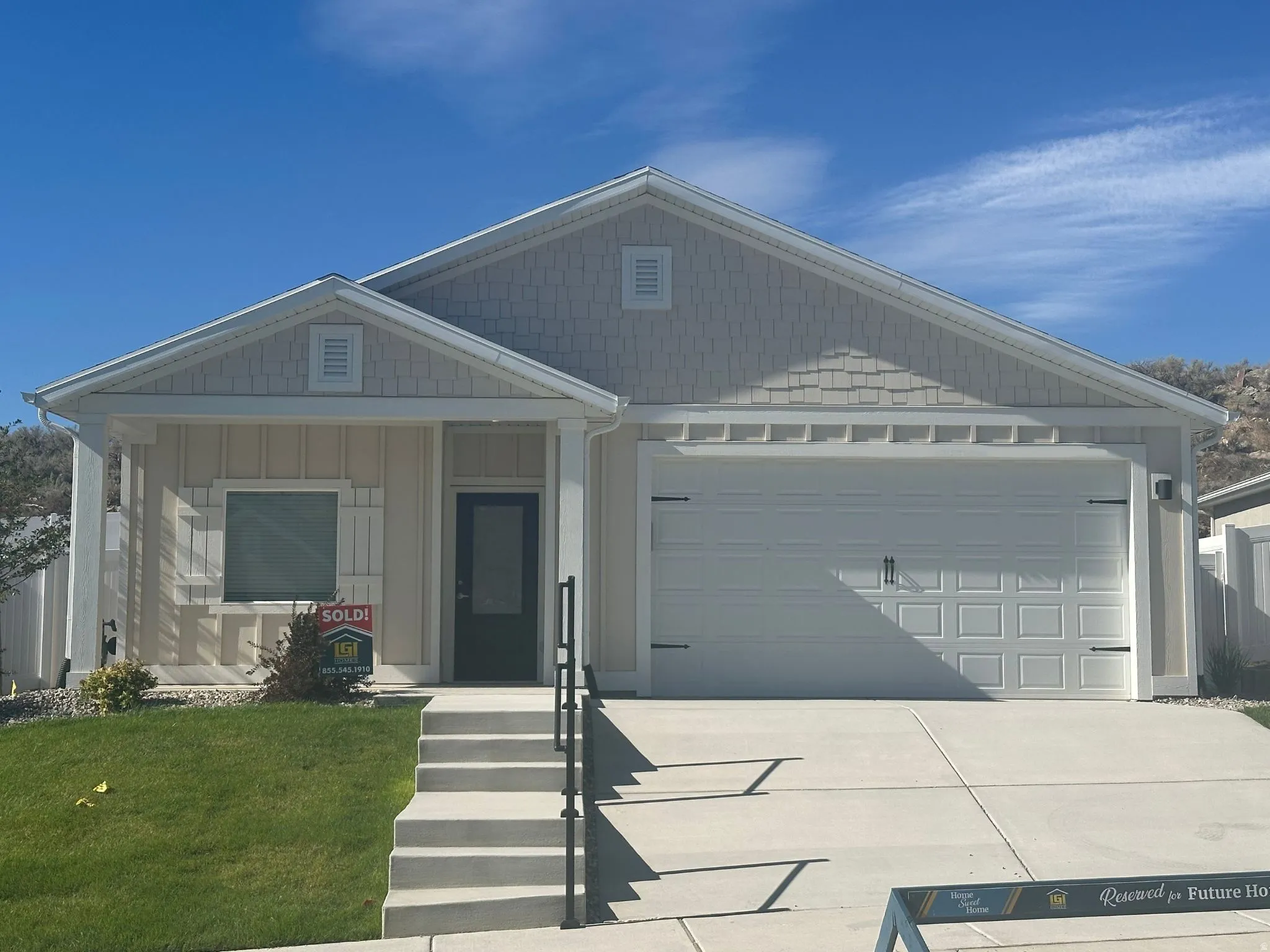 Single-story home featuring a two-car garage with decorative hardware, a covered front entry, and concrete steps with a black metal handrail