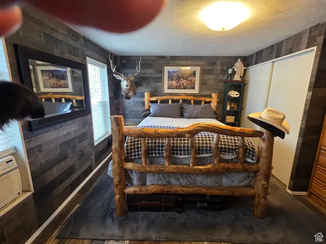 Bedroom featuring a textured ceiling and wooden walls