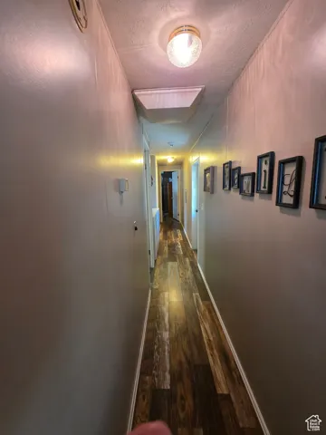 Hallway featuring dark wood-style flooring and a textured ceiling