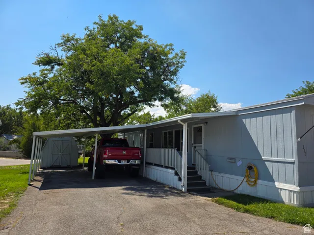 View of side of home with a shed, driveway, and a carport
