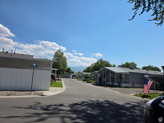 View of asphalt street featuring a residential view and curbs