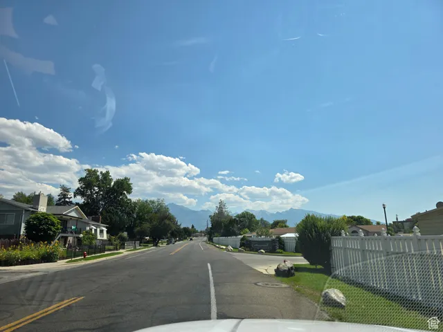 View of asphalt street featuring sidewalks, a residential view, and a mountain view