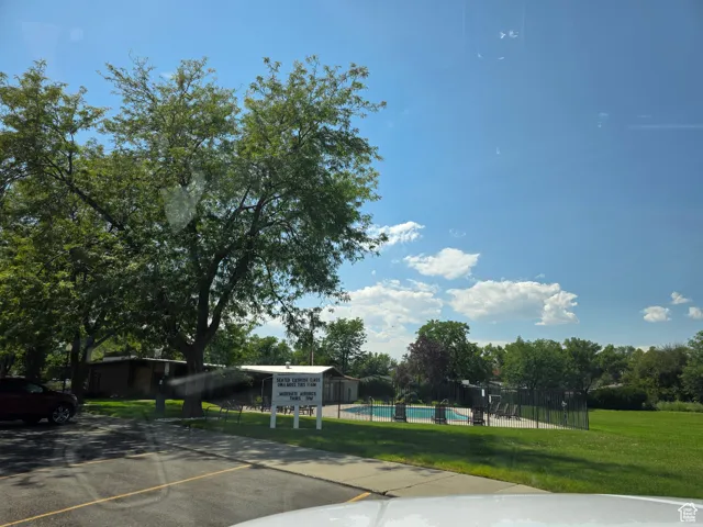 Surrounding community featuring a pool, view of scattered trees, and uncovered parking