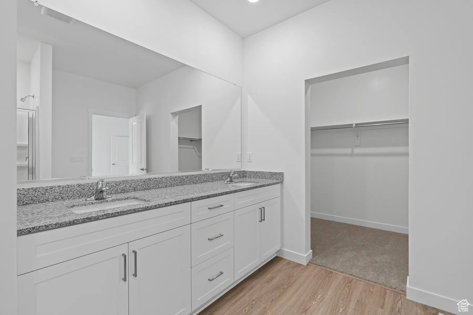 Bathroom featuring light wood-style flooring, a spacious closet, and double vanity