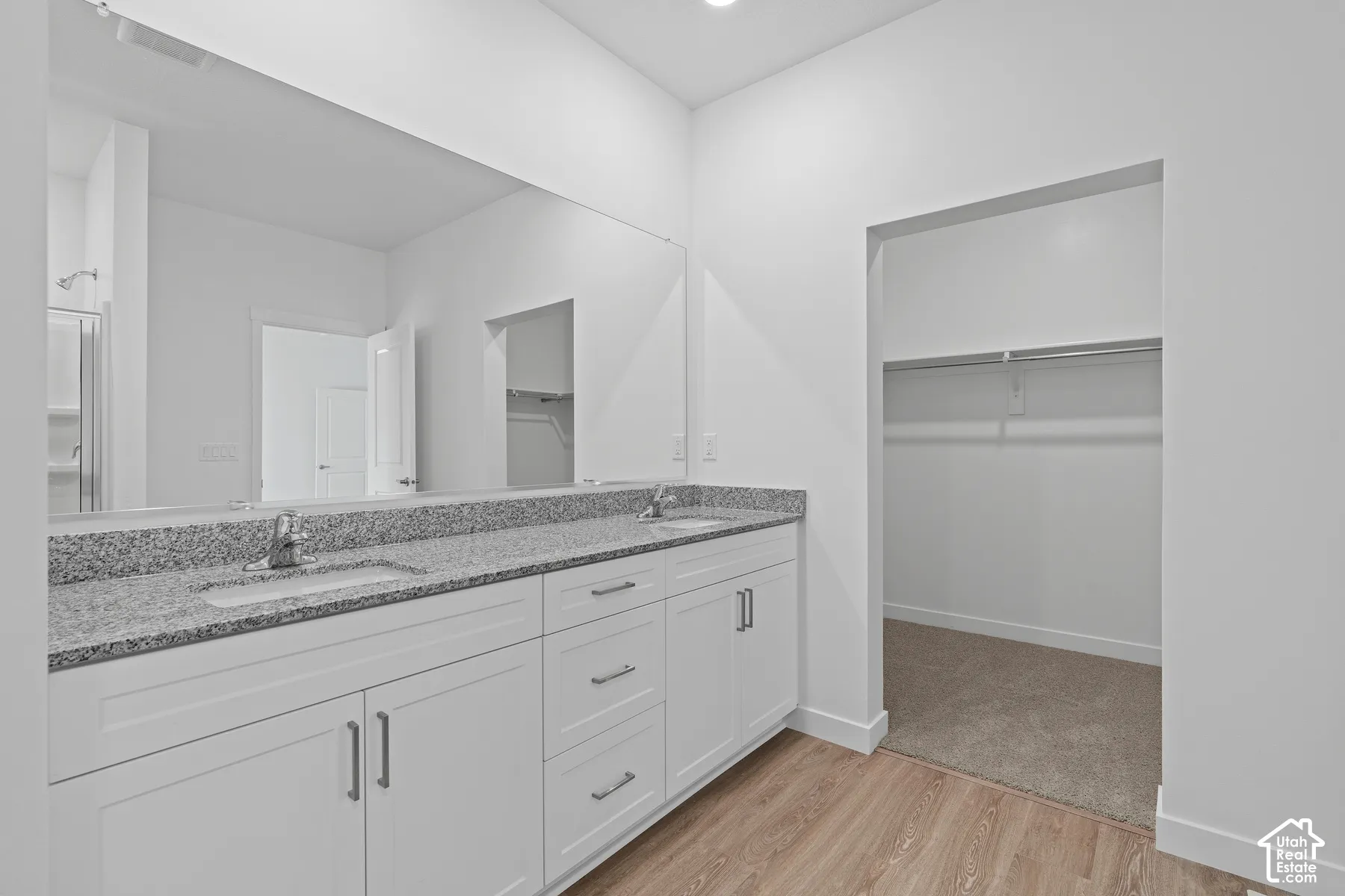 Bathroom featuring light wood-style flooring, a spacious closet, and double vanity