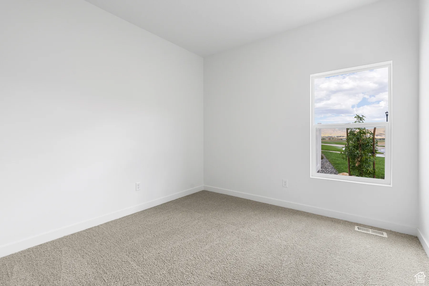 Carpeted spare room featuring baseboards