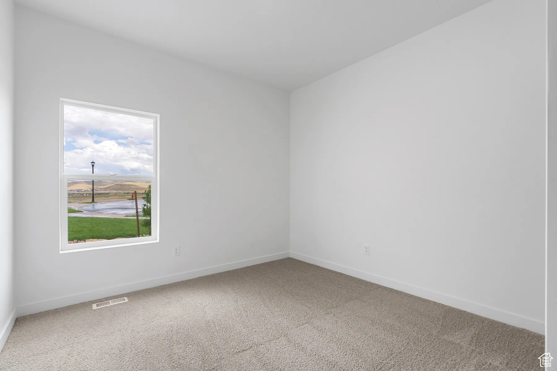 Spare room featuring light carpet and baseboards