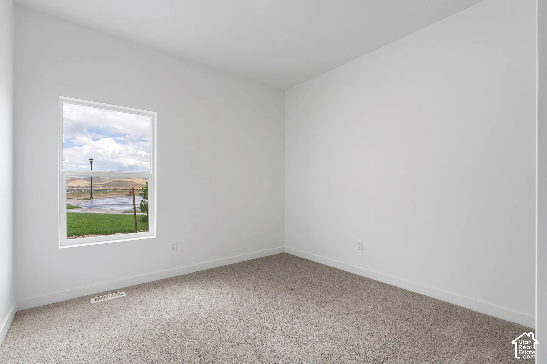 Spare room featuring light carpet and baseboards