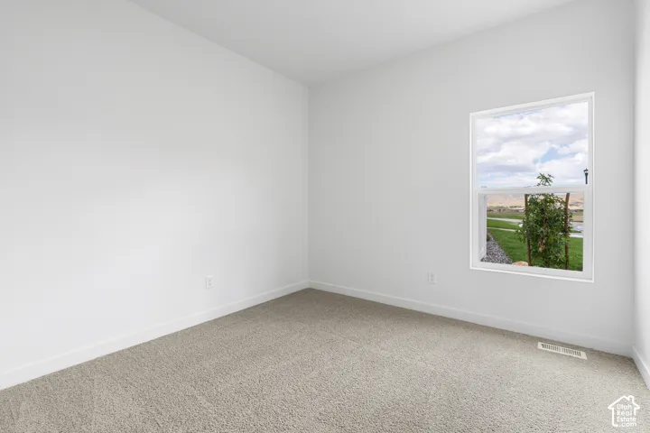 Carpeted spare room featuring baseboards