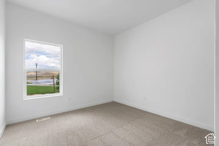 Spare room featuring light carpet and baseboards