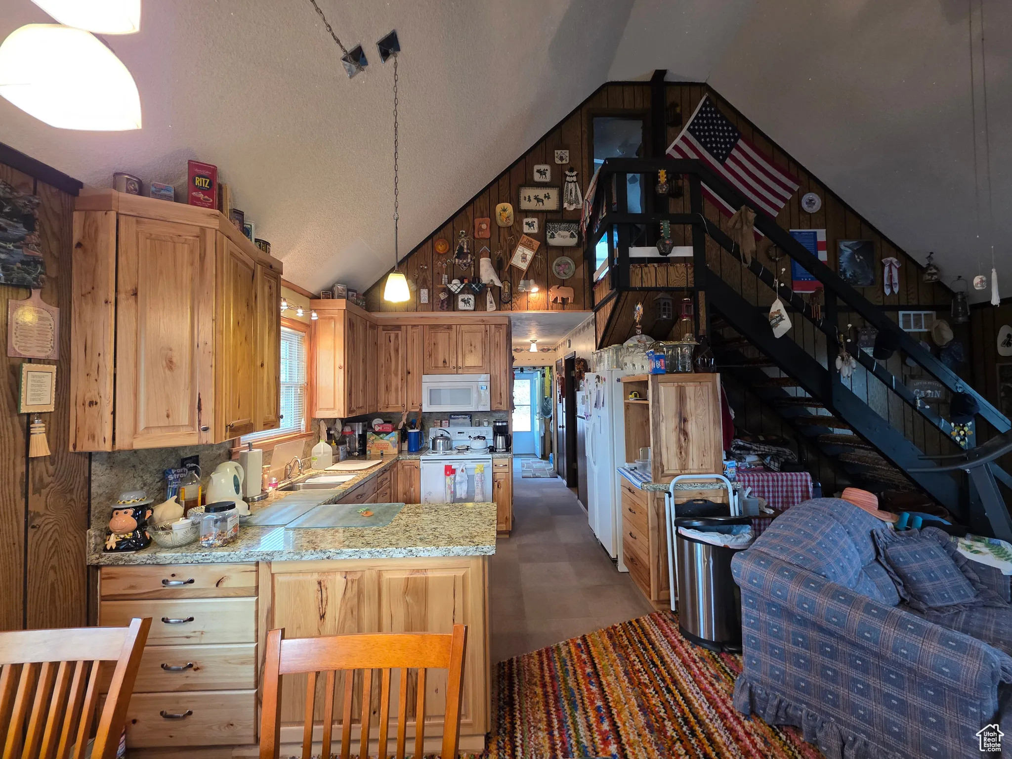Kitchen featuring light countertops, decorative light fixtures, range, white microwave, and a peninsula