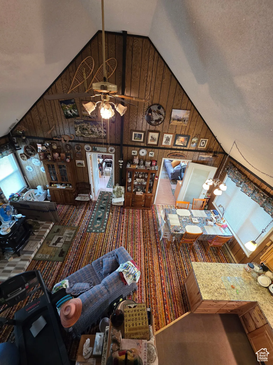 Living room featuring wooden walls, high vaulted ceiling, a textured ceiling, and a ceiling fan