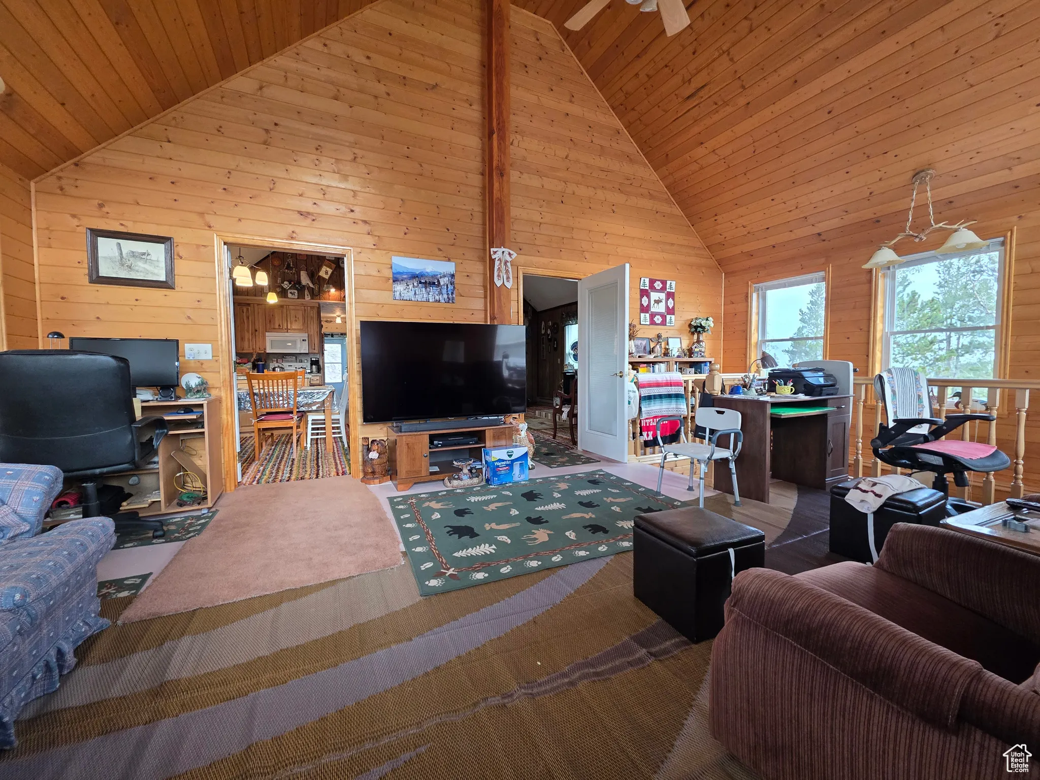 Living area with wooden walls, a desk, high vaulted ceiling, carpet flooring, and wood ceiling