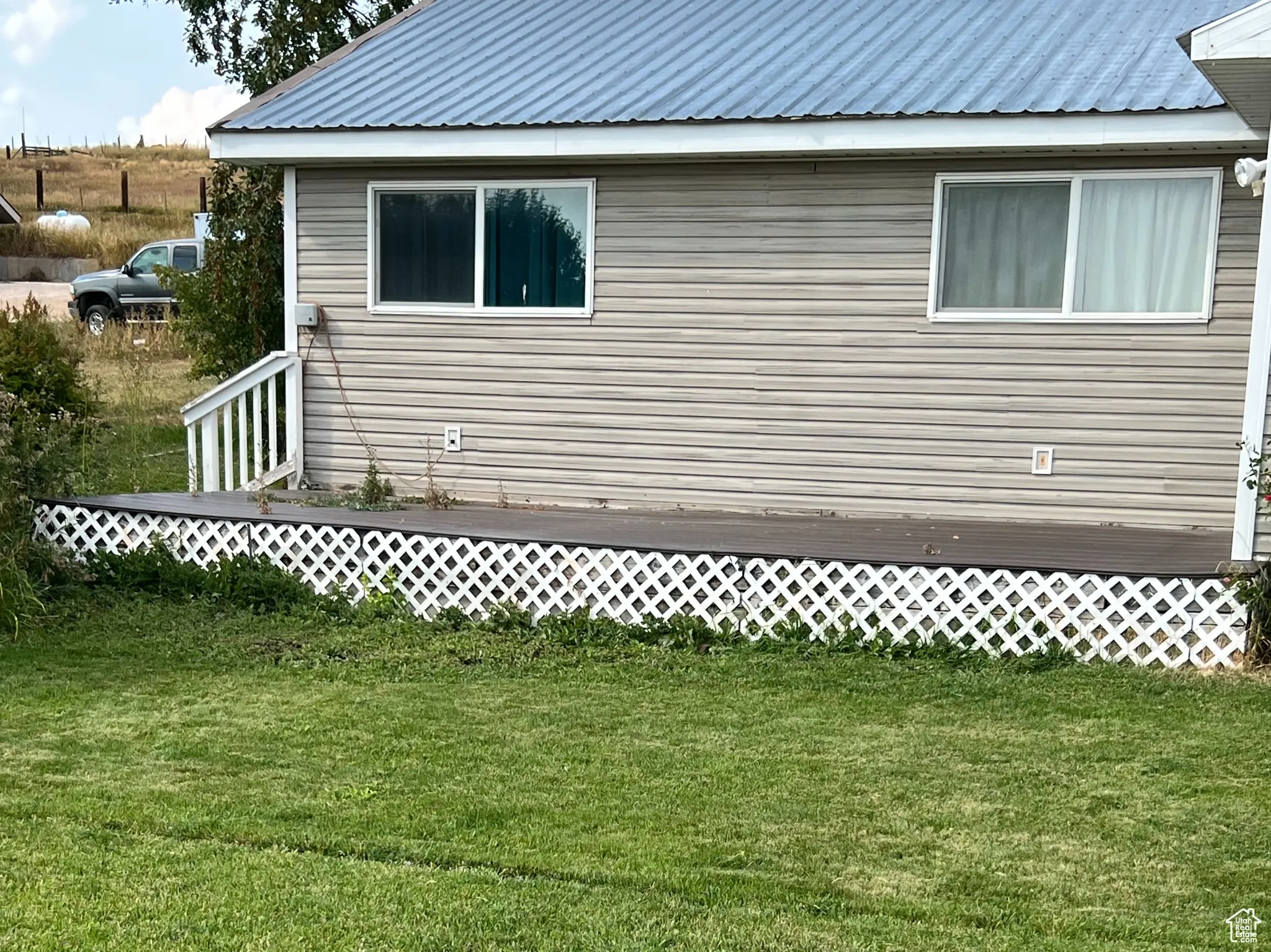View of side of property with a metal roof and a lawn