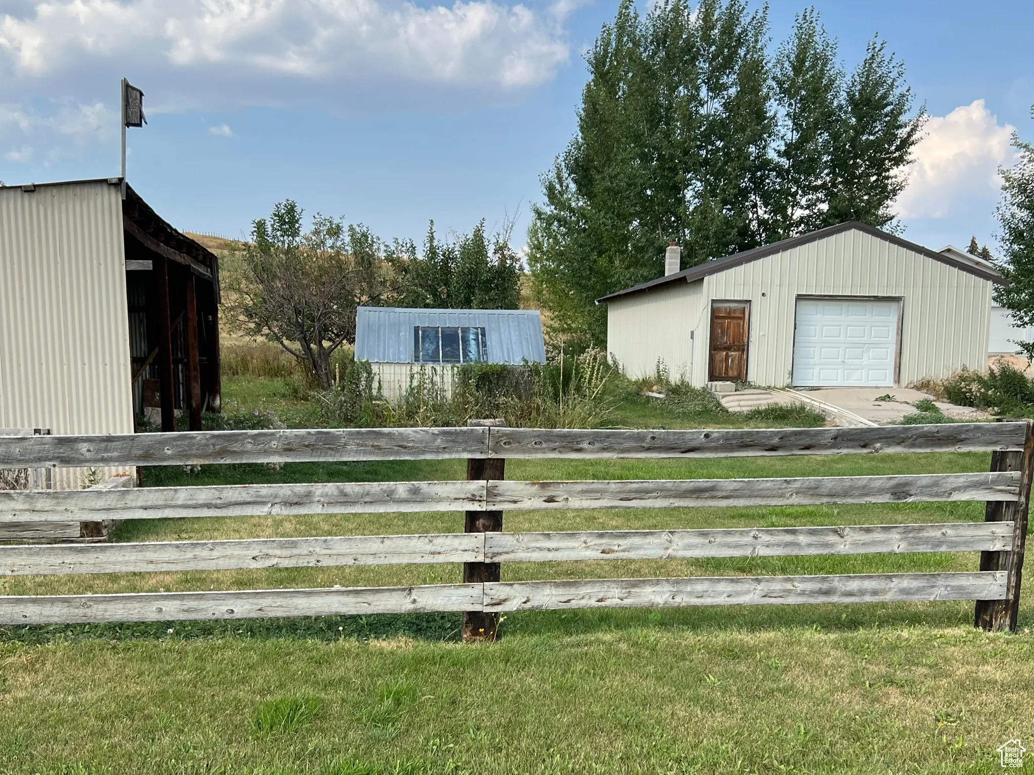 View of grassy yard with an outdoor structure, a pole building, and a garage