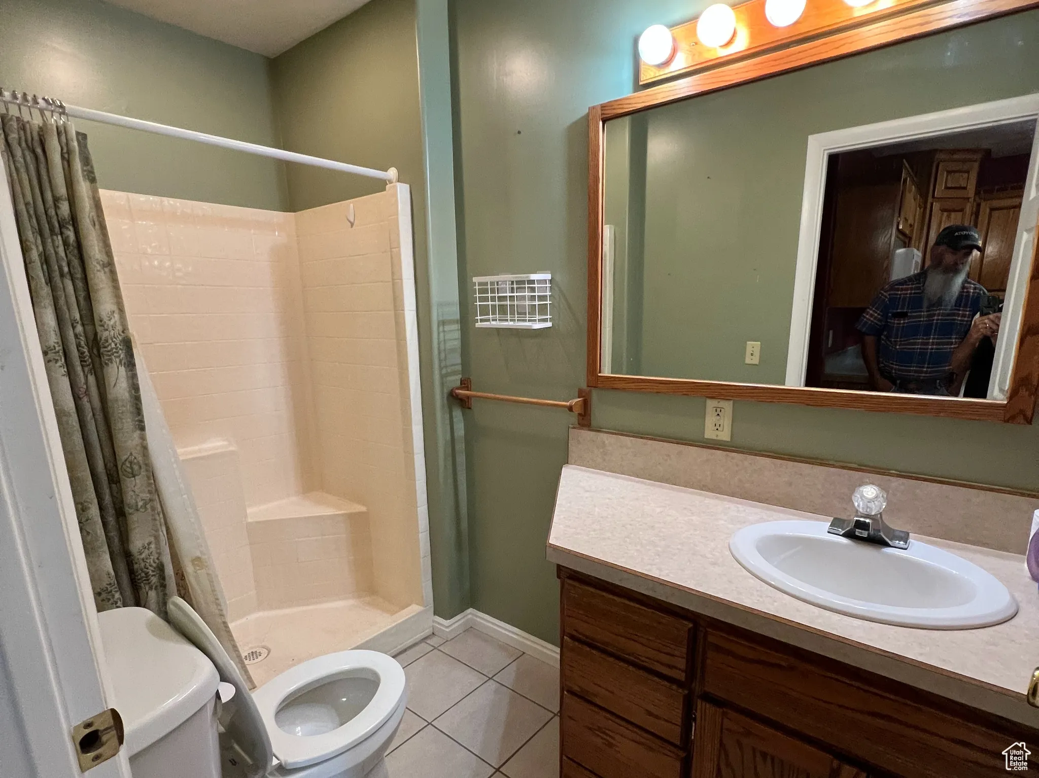 Full bath featuring light tile patterned floors, vanity, and a stall shower