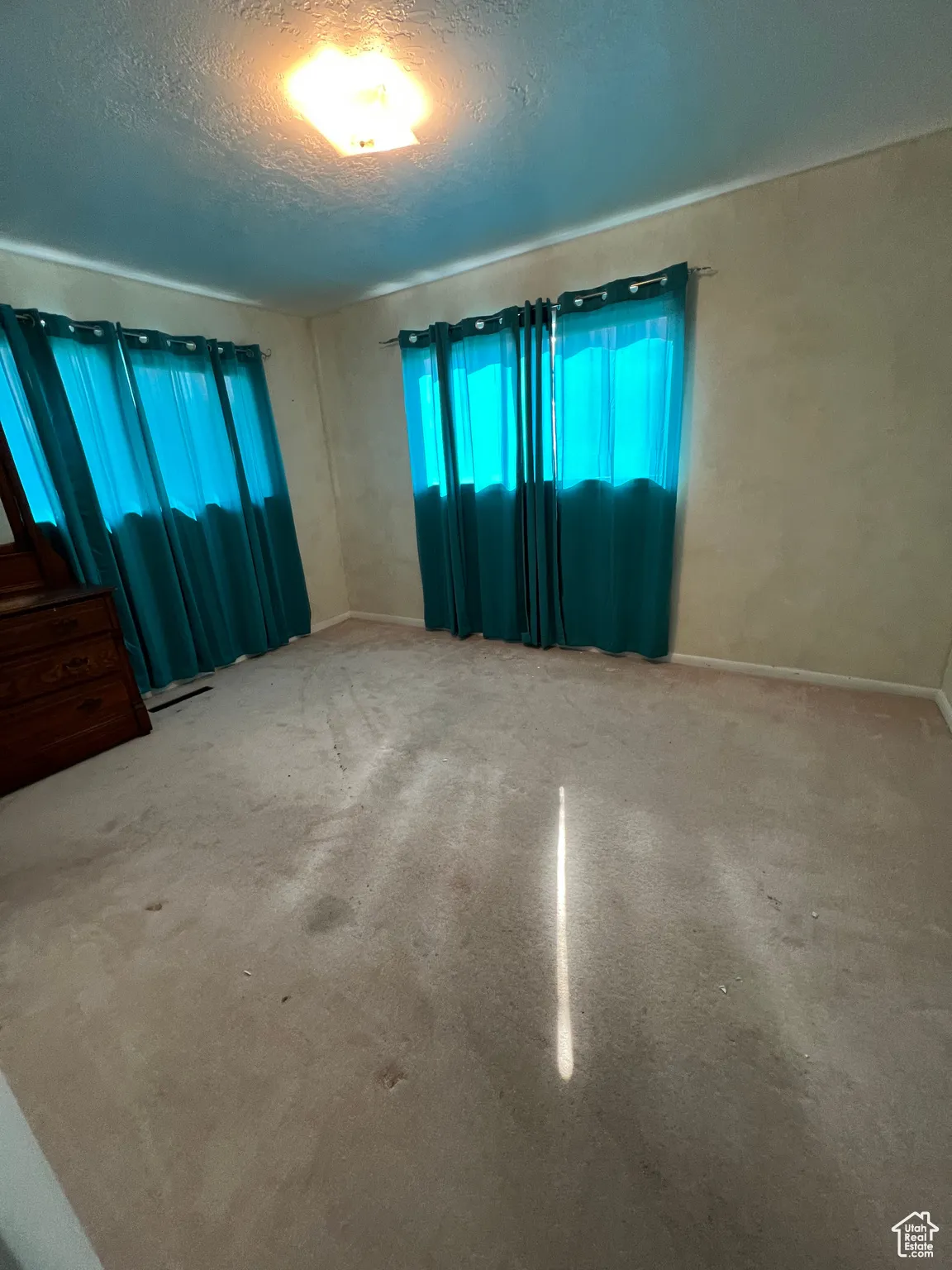 Unfurnished room featuring a textured ceiling and carpet