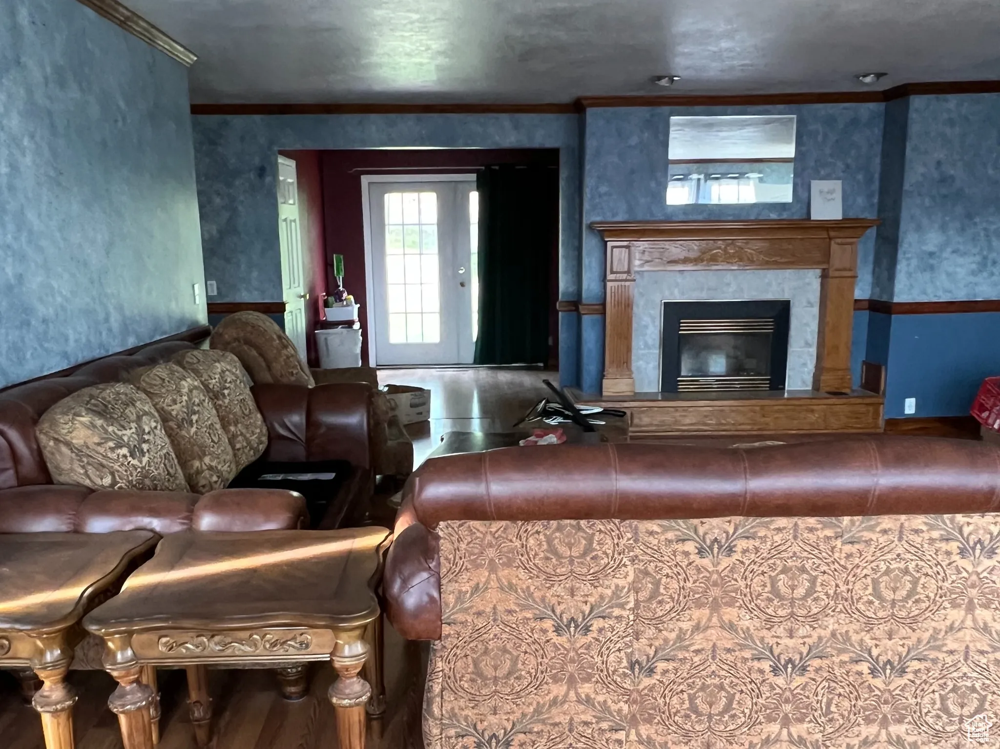 Living area with a tiled fireplace, ornamental molding, wood finished floors, and a textured ceiling