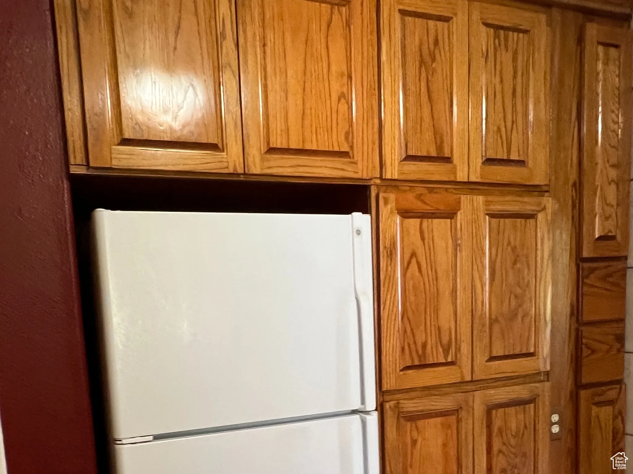 Kitchen with brown cabinets, freestanding refrigerator, and light wood-style flooring