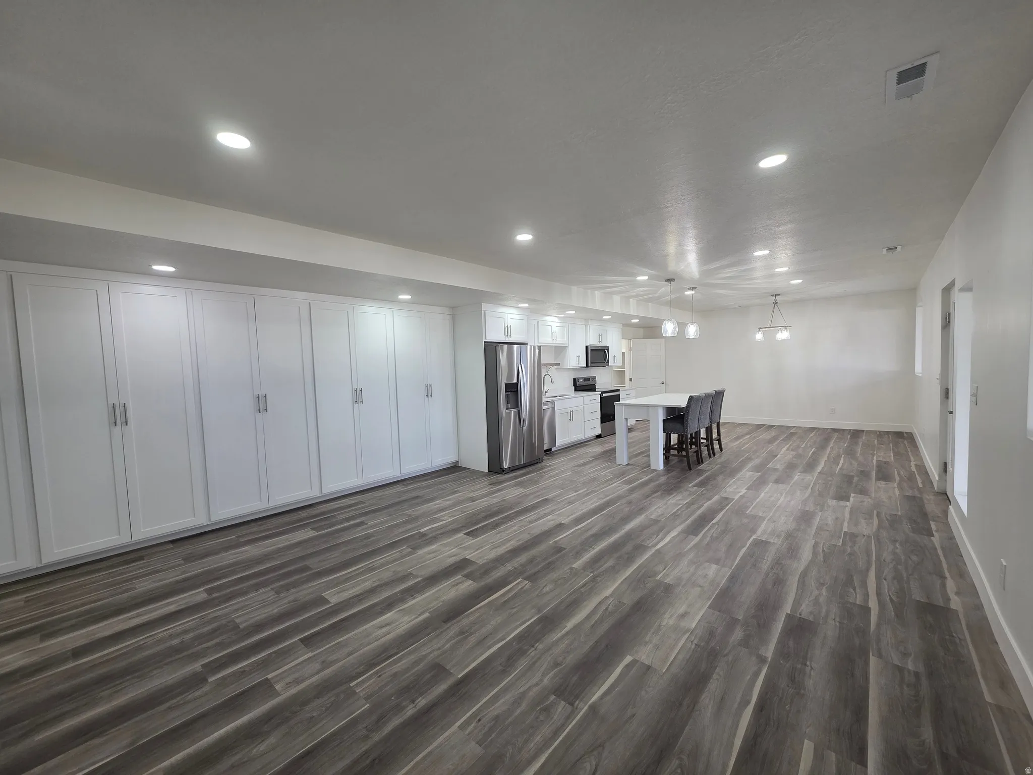 Unfurnished living room with dark wood-type flooring and recessed lighting