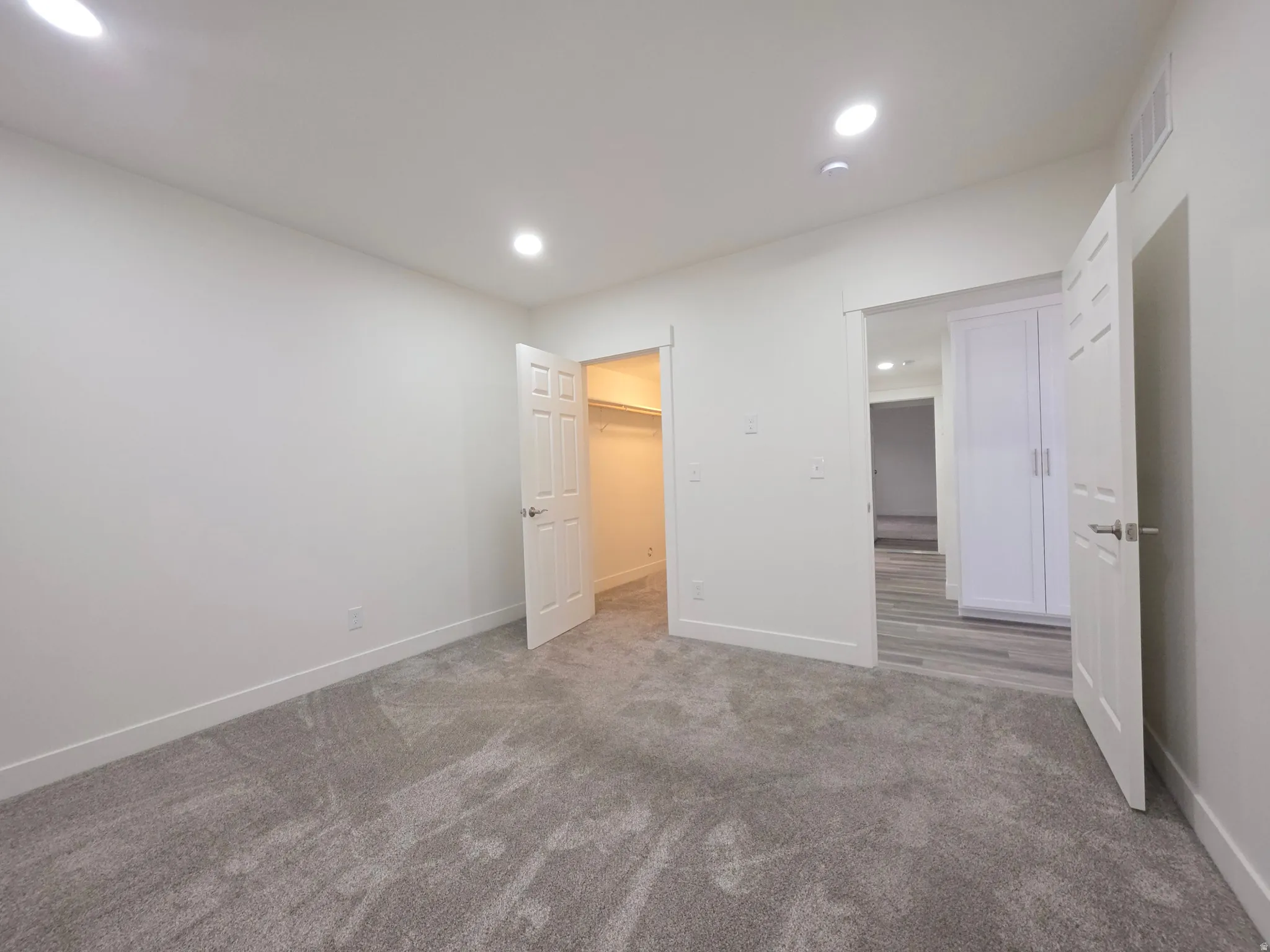 Unfurnished bedroom featuring a spacious closet, carpet floors, and recessed lighting