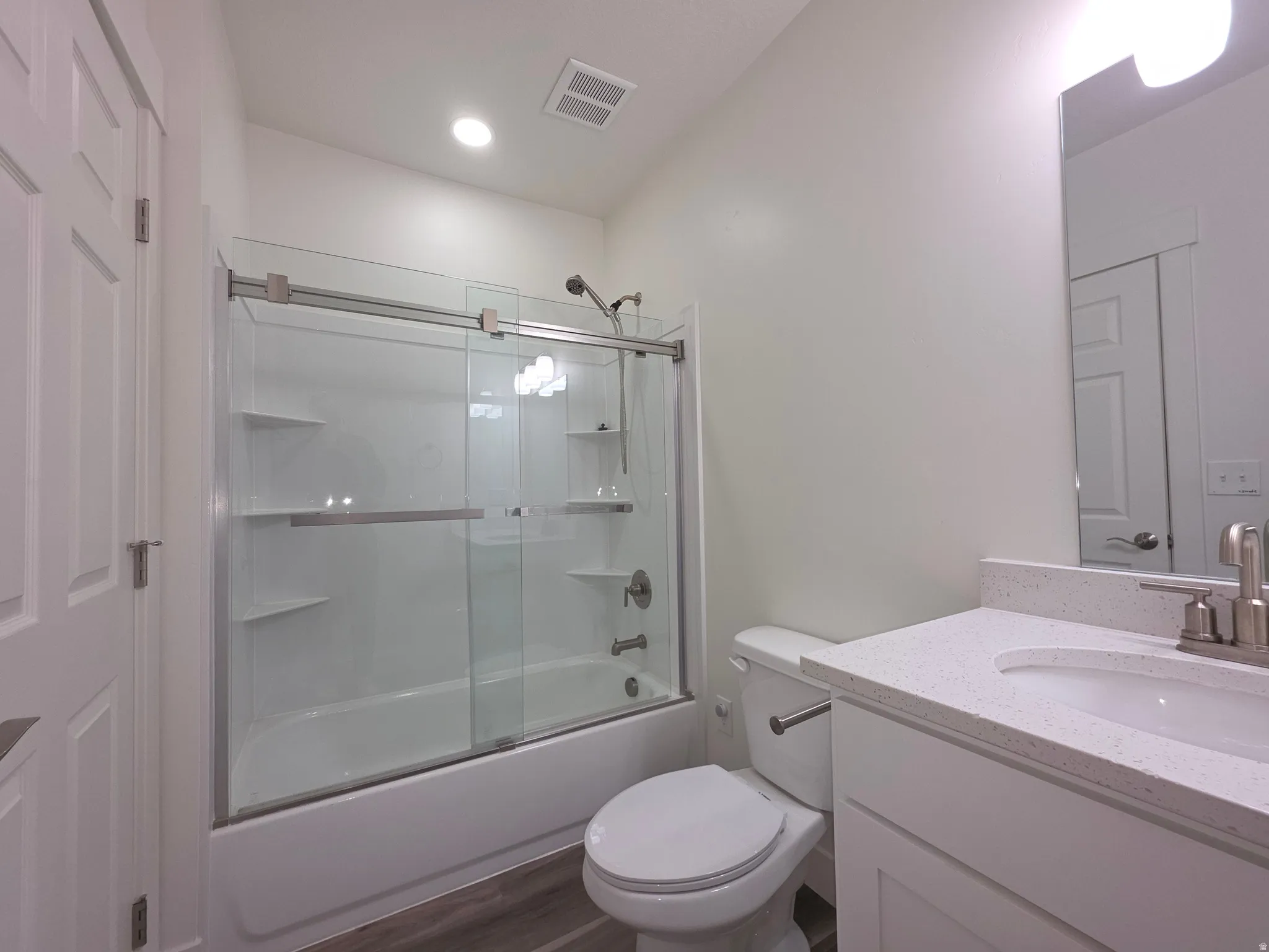 Bathroom with vanity, shower / bath combination with glass door, and dark wood finished floors
