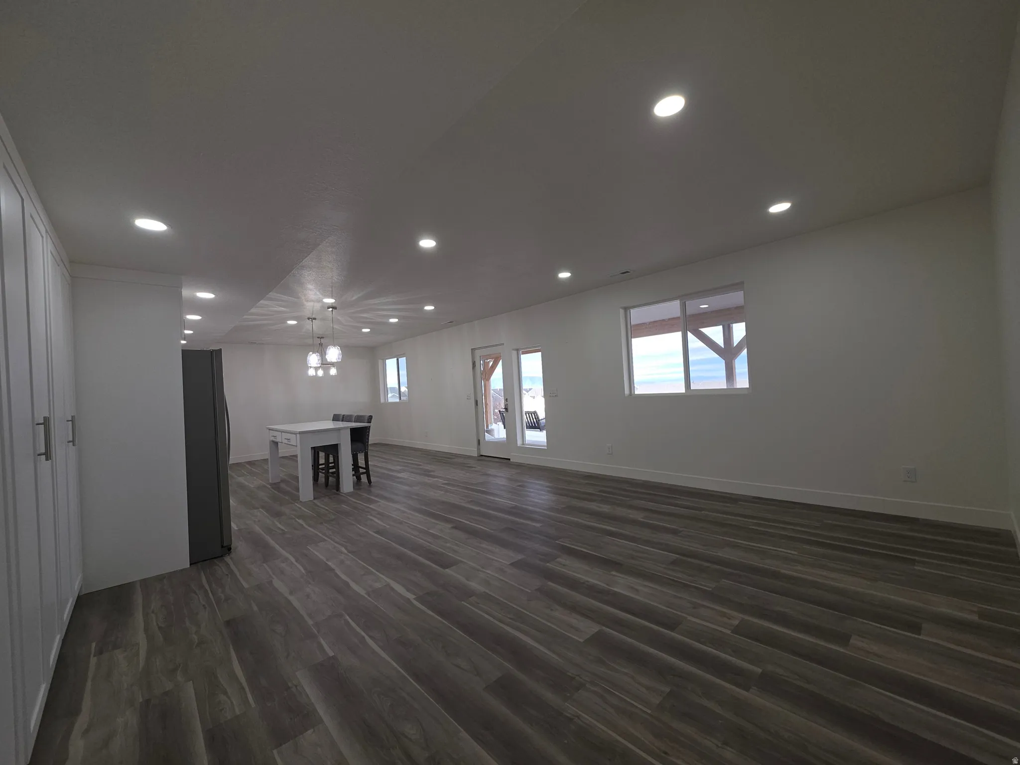 Unfurnished living room featuring dark wood finished floors, recessed lighting, and a chandelier