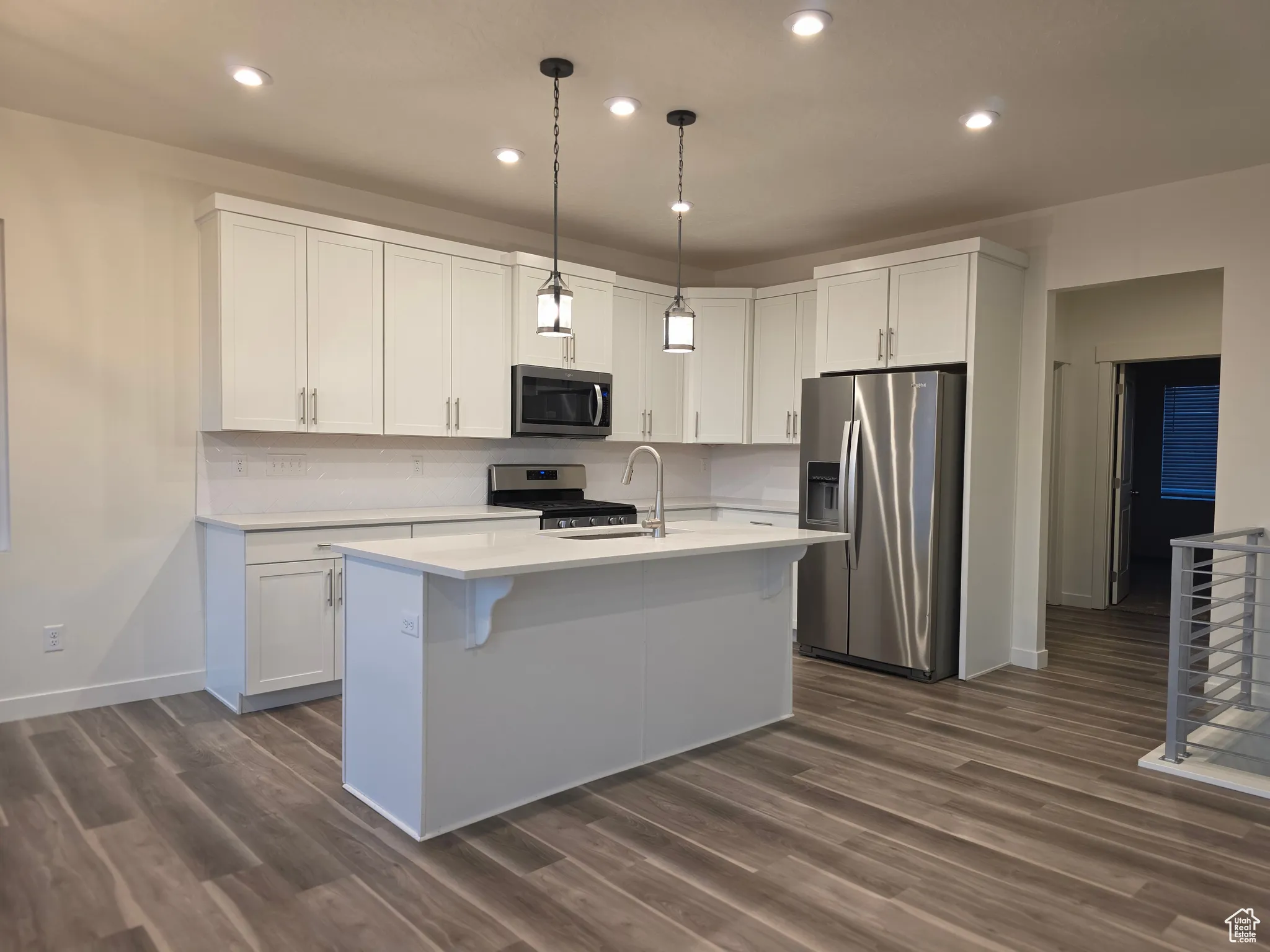 Kitchen featuring appliances with stainless steel finishes, white cabinets, pendant lighting, recessed lighting, and dark wood-style flooring