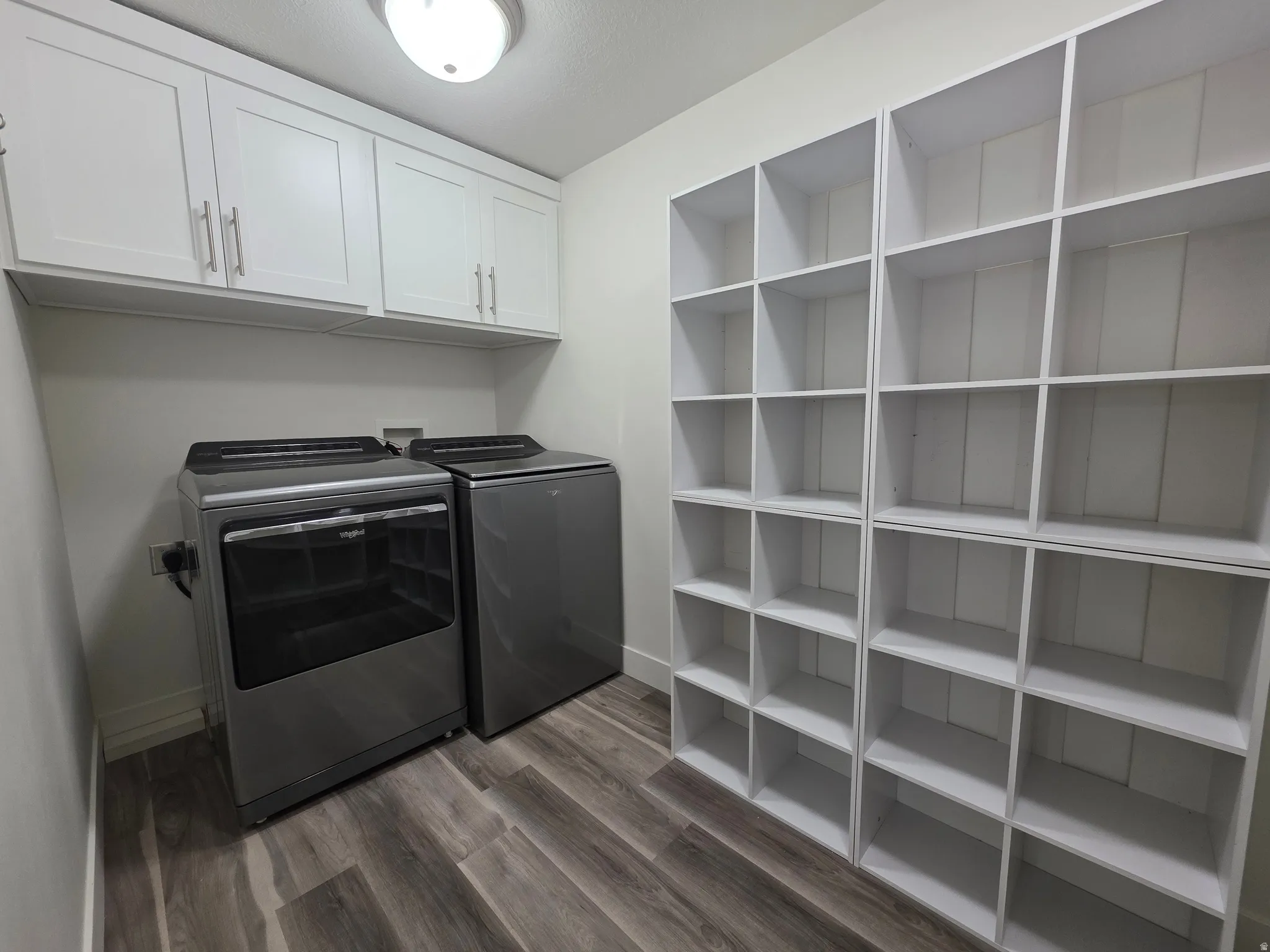 Washroom featuring dark wood-type flooring, washer and dryer, and cabinet space