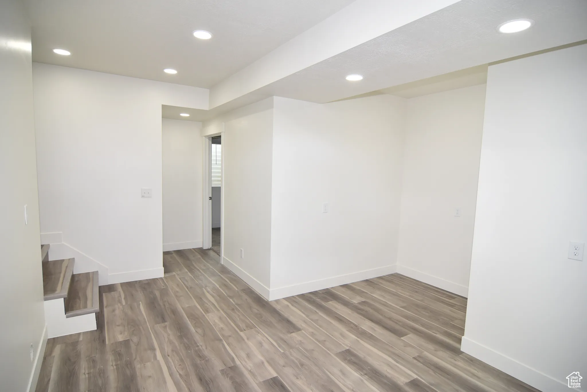 Unfurnished room with recessed lighting, wood finished floors, and stairway
