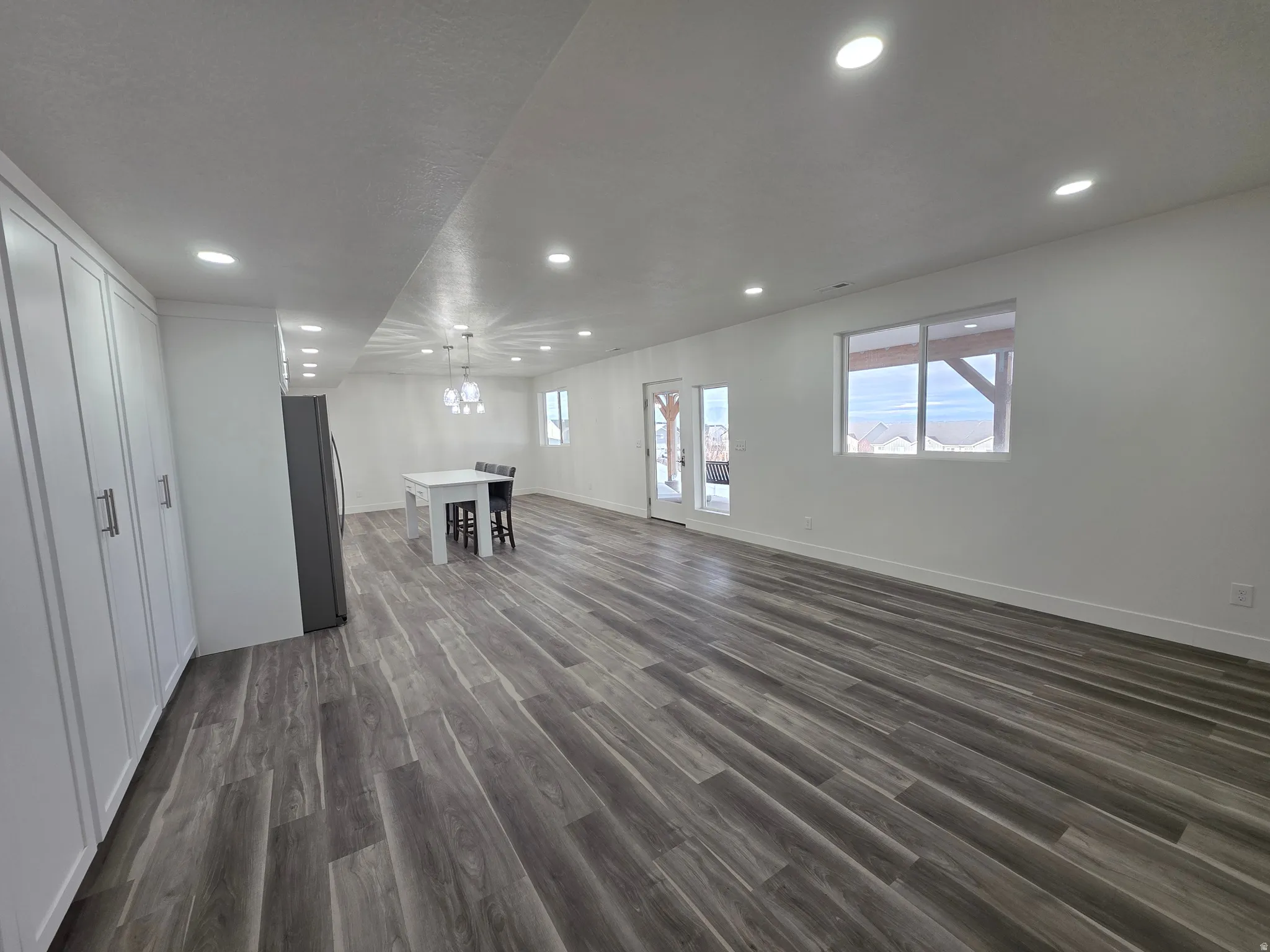 Unfurnished living room featuring dark wood-style floors, recessed lighting, and plenty of natural light
