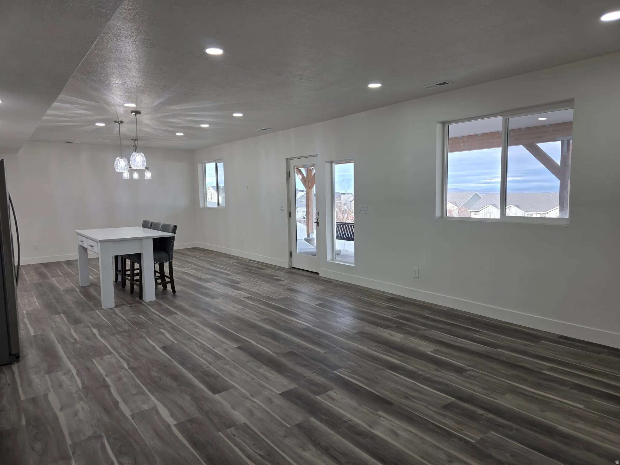 Unfurnished dining area featuring recessed lighting, dark wood-style floors, plenty of natural light, and a textured ceiling