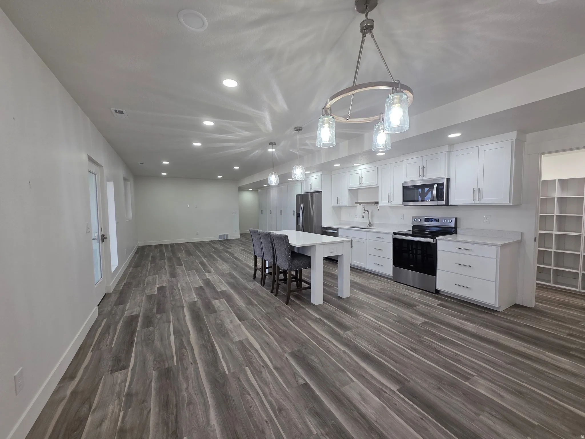 Kitchen featuring recessed lighting, white cabinetry, open floor plan, decorative light fixtures, and stainless steel appliances