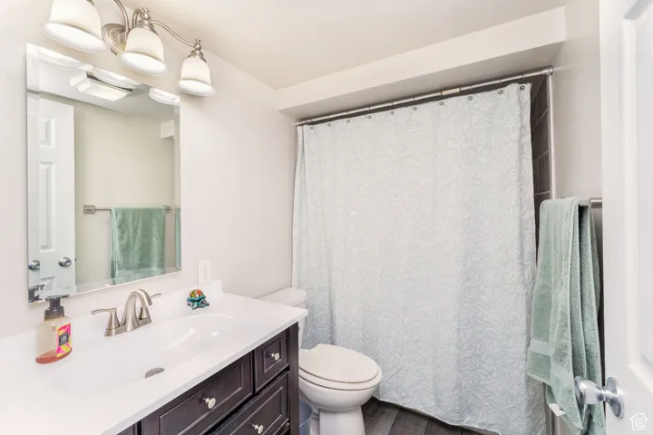 Full bathroom with vanity, dark wood-style floors, and a shower with curtain