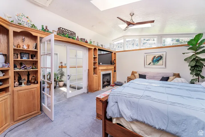 Bedroom featuring a textured ceiling, light colored carpet, lofted ceiling, ceiling fan, and a fireplace