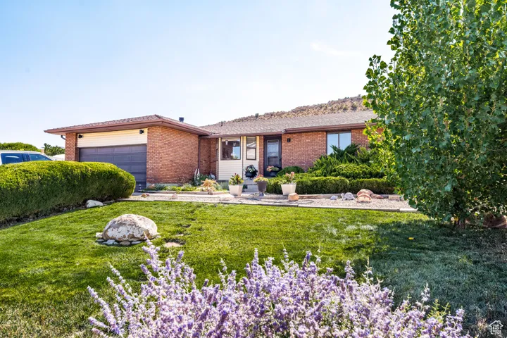 Ranch-style house with brick siding, a front lawn, and a garage