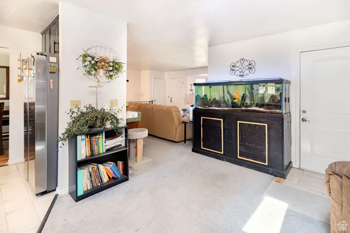 Kitchen featuring freestanding refrigerator, a textured ceiling, and light carpet