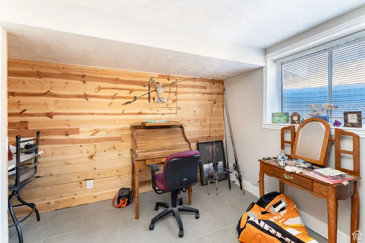Tiled home office featuring wooden walls and baseboards