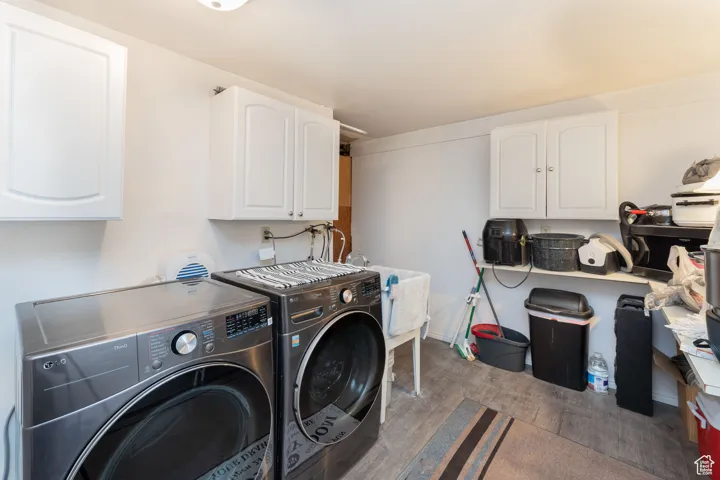 Washroom featuring wood finished floors, washing machine and dryer, and cabinet space