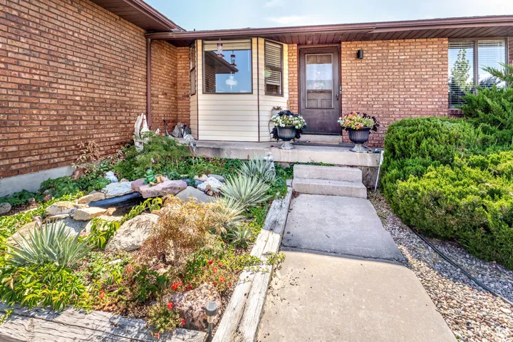 Entrance to property with brick siding, covered porch, and a garden pond