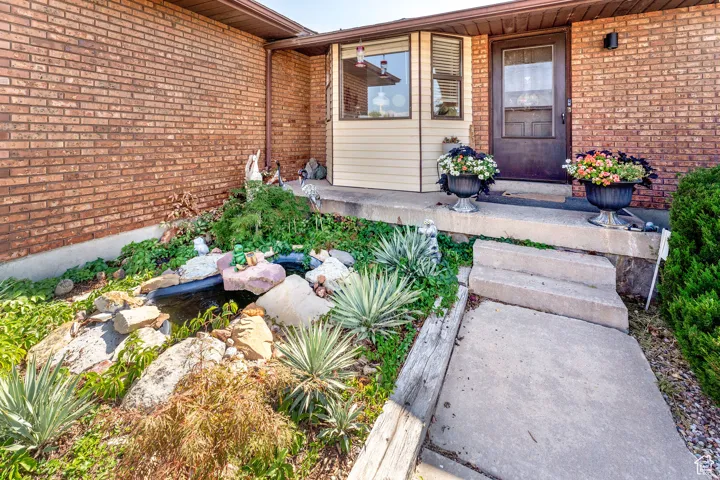 Entrance to property with brick siding and a small pond