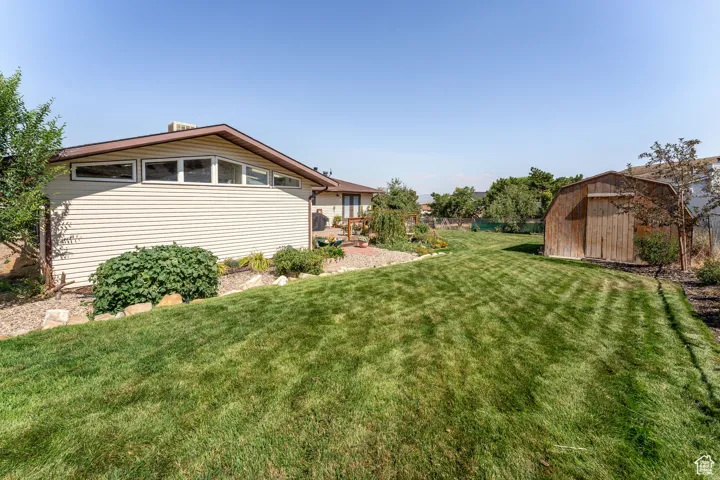 View of green lawn featuring a storage shed